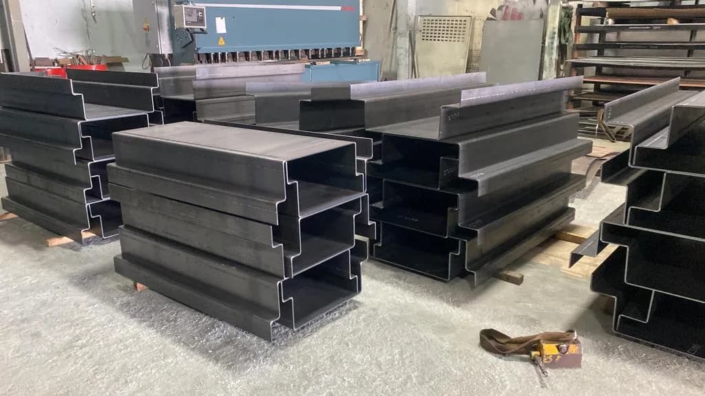 Palletised stacks of heavy bent sheet metal profiles in the workshop