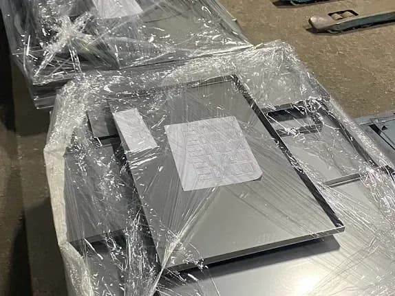 Powder-coated grey sheet panels, shrink-wrapped on a pallet